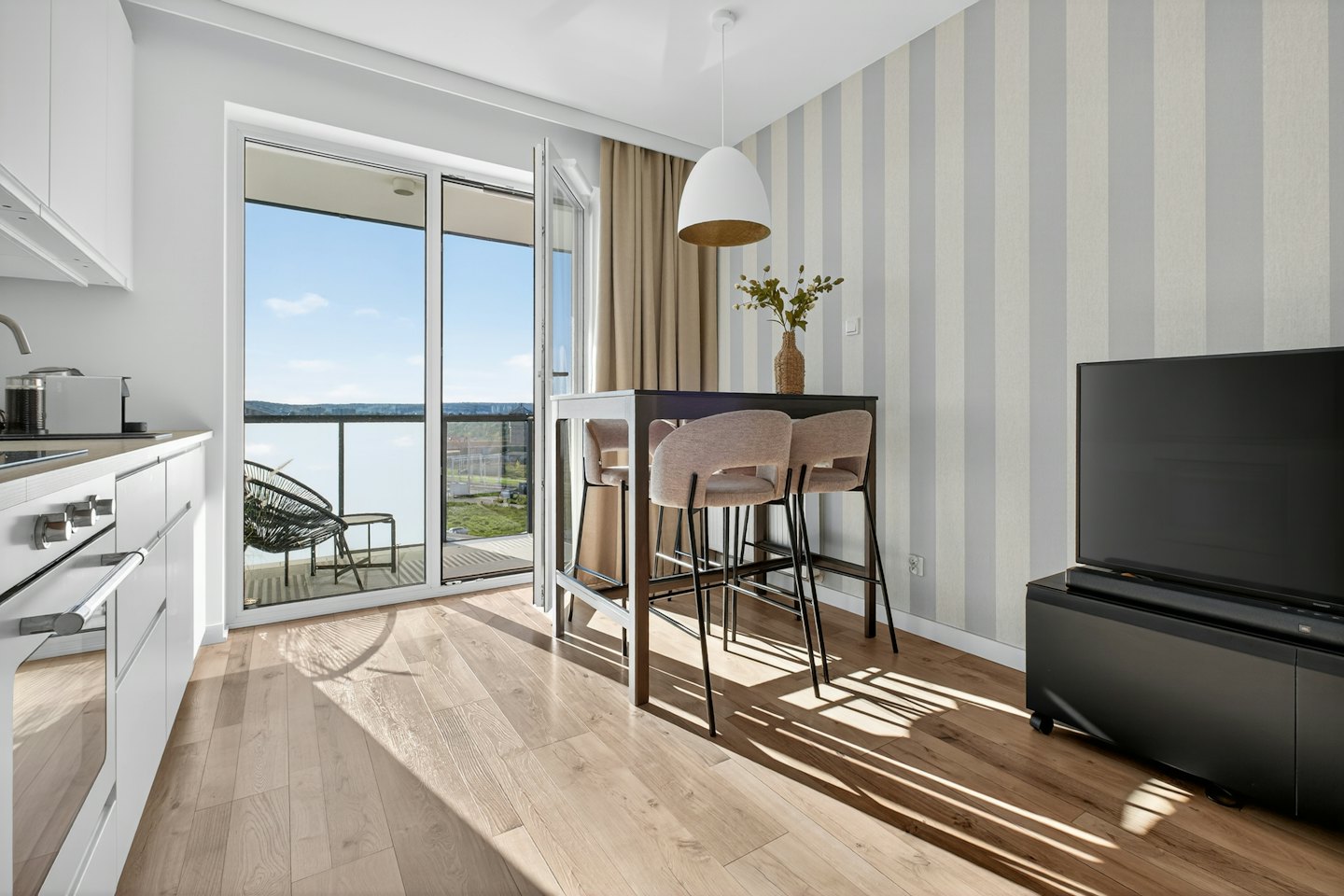 Interno di un moderno appartamento con cucina, zona pranzo e vista sul balcone.